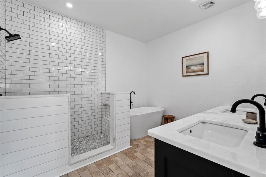 Bathroom with a walk in shower, double vanity, a freestanding bath, and recessed lighting