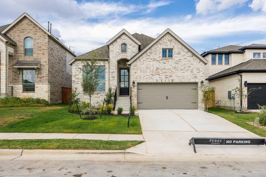 French provincial home featuring brick siding, a front yard, driveway, a garage, and a shingled roof French provincial home featuring brick siding, a front yard, driveway, a garage, and a shingled roof