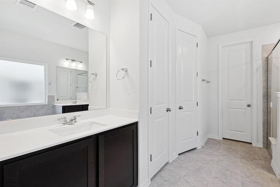 Bathroom featuring vanity, walk in shower, and tile patterned flooring