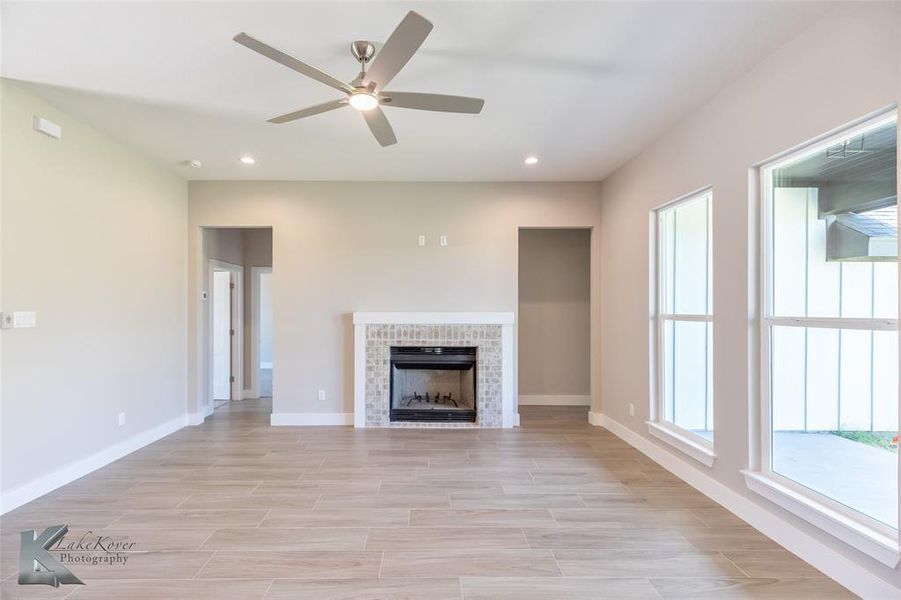 Unfurnished living room featuring a ceiling fan, recessed lighting, and a tiled fireplace
