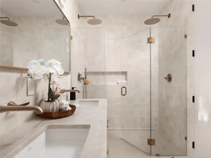 A well-appointed primary bathroom features dual vanities and a spacious walk-in shower with twin rain shower heads. A well-appointed primary bathroom features dual vanities and a spacious walk-in shower with twin rain shower heads.