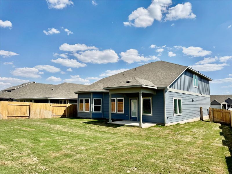 Back of house featuring a fenced backyard, a patio, and a shingled roof