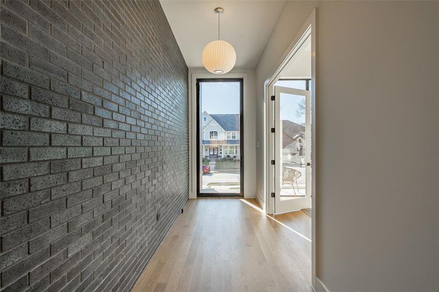 Entryway with brick wall and light hardwood / wood-style flooring