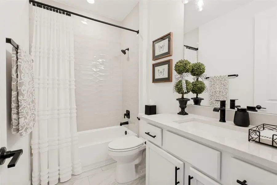 Polished tile surrounds a tub and shower pairing adjacent to a sleek stone-topped vanity.