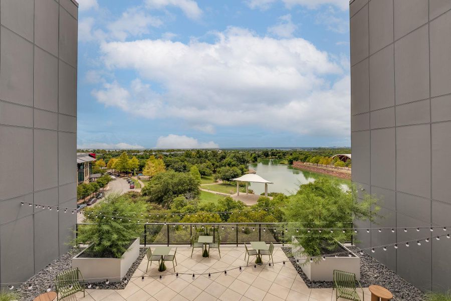 Spacious outdoor patio area with tiled flooring and string lights, offering expansive views of a lake and green landscape