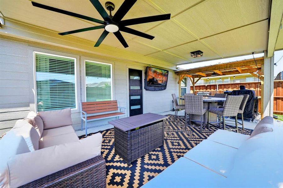Covered patio featuring a large ceiling fan, recessed lighting, and a mounted television