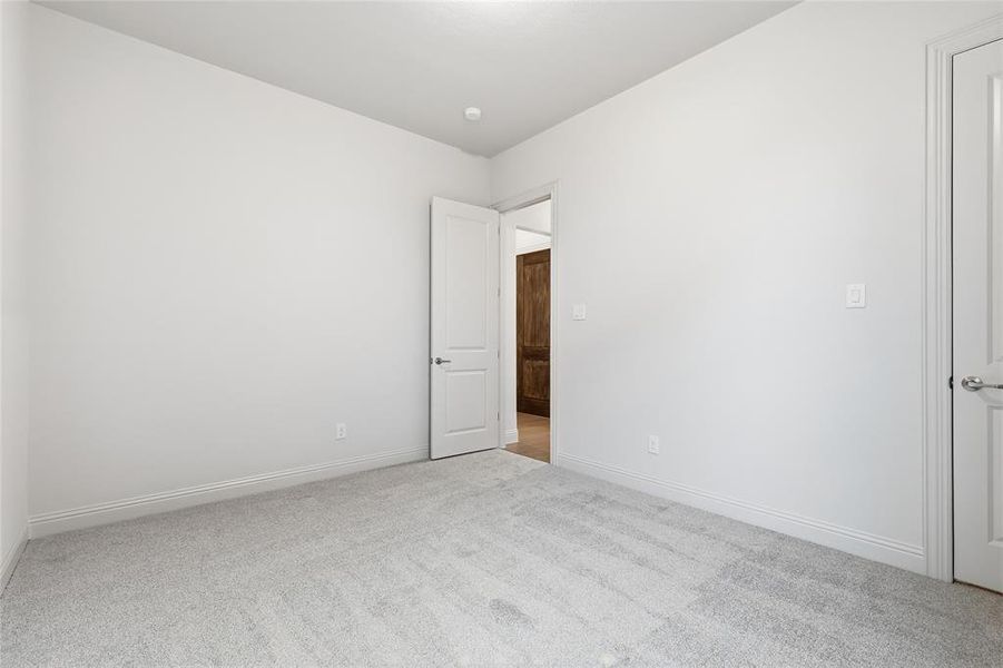 Unfurnished bedroom with light carpet and baseboards
