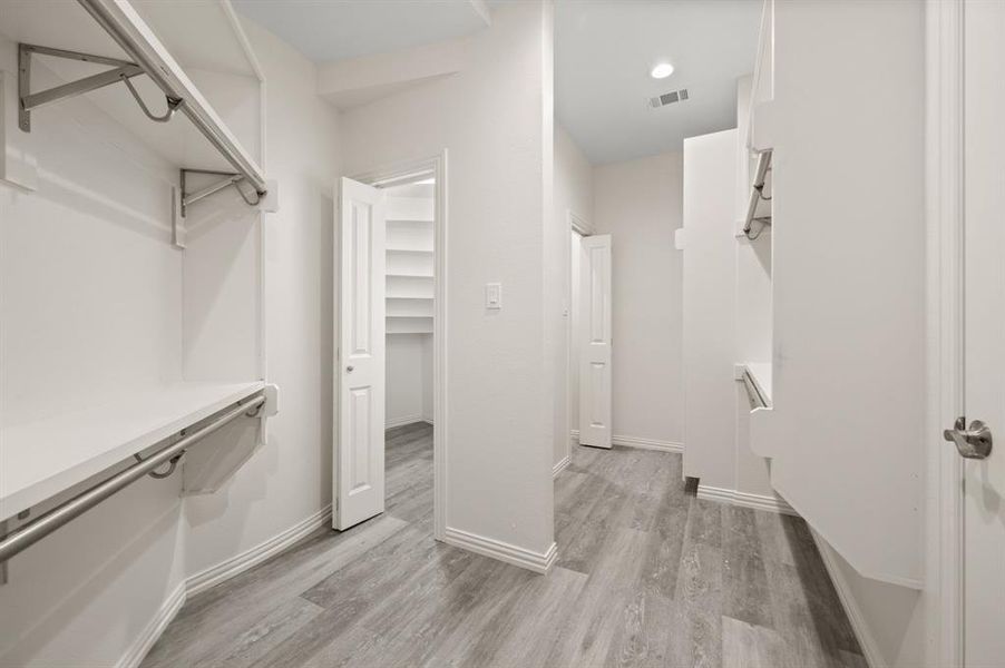 Walk in closet with light wood-style floors Walk in closet with light wood-style floors