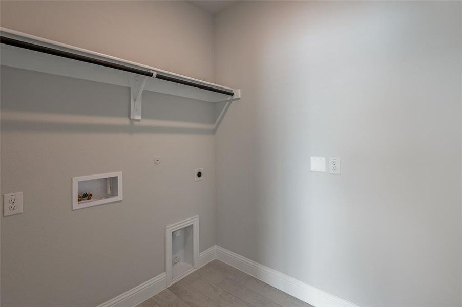 Dedicated utility space featuring light gray walls, wood-finish flooring, and crisp white baseboards