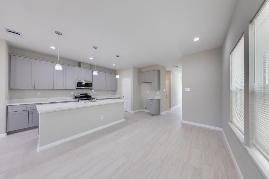 Step into the sleek, modern kitchen, where brand new stainless steel appliances perfectly complement the stylish grey cabinetry.
