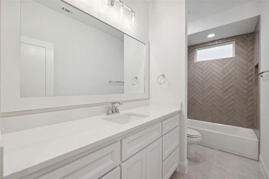 Full bathroom with vanity, tile patterned flooring, toilet, and tiled shower / bath combo