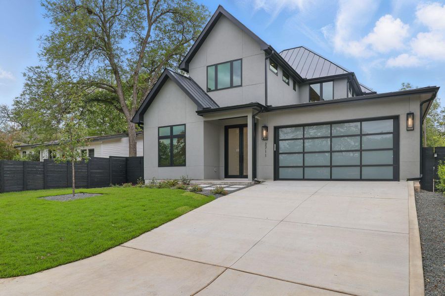View of front of house with stucco siding, driveway, a garage, a metal roof, and a standing seam roof