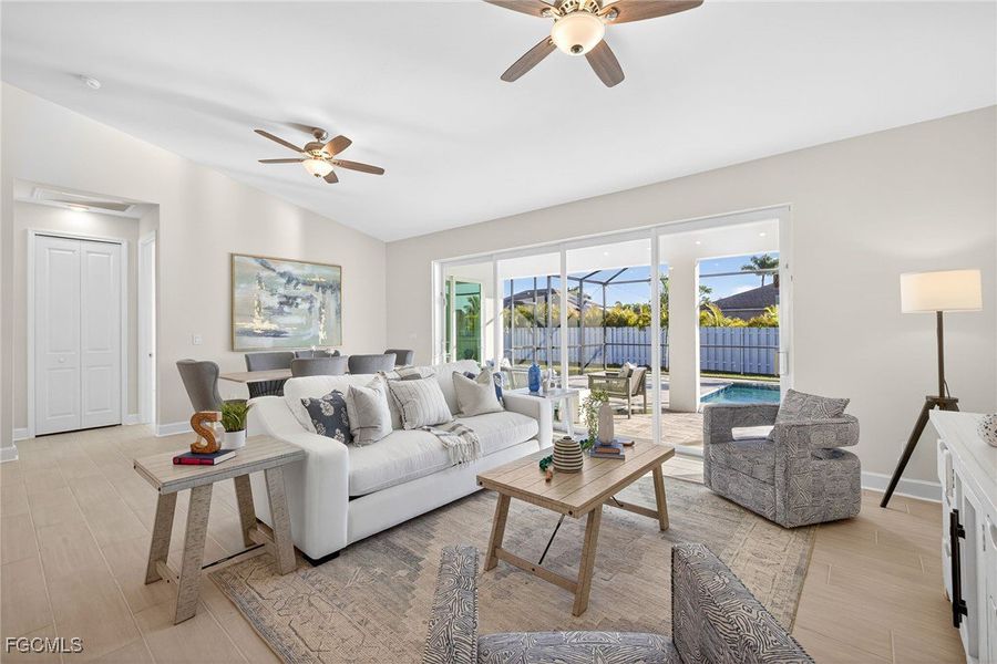 Living area with vaulted ceiling, ceiling fan, and light wood-style flooring