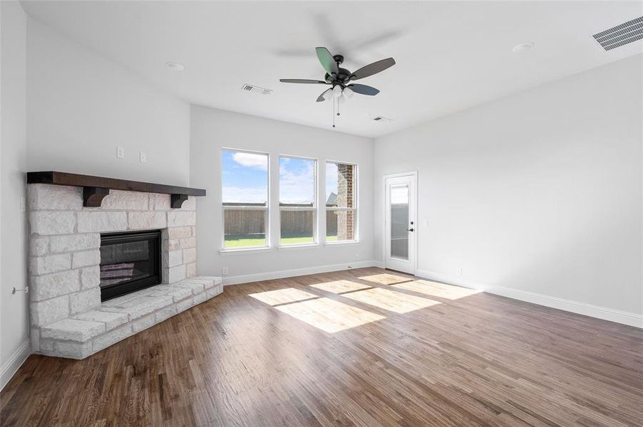 Unfurnished living room featuring wood finished floors, a fireplace, and a ceiling fan