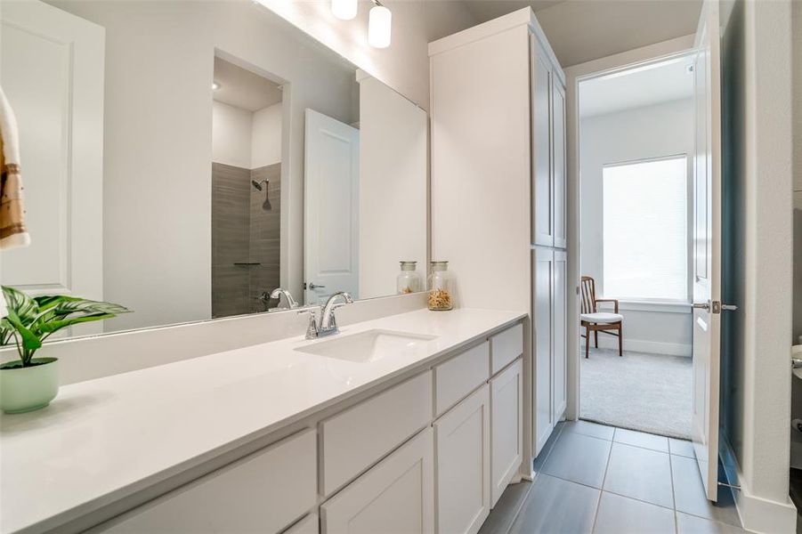 This view shows the Jack and Jill bath which has a tub and shower and a large linen cabinet.