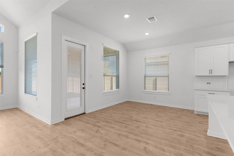 Unfurnished dining area featuring light wood finished floors, recessed lighting, and vaulted ceiling