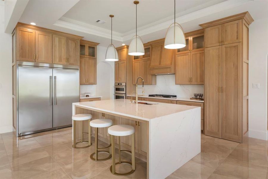 The Perfect Blonde White Oak cabinetry with all Frigidaire Professional Series stainless steel appliances, a quartz waterfall island with seating, and elegant pendant lighting.