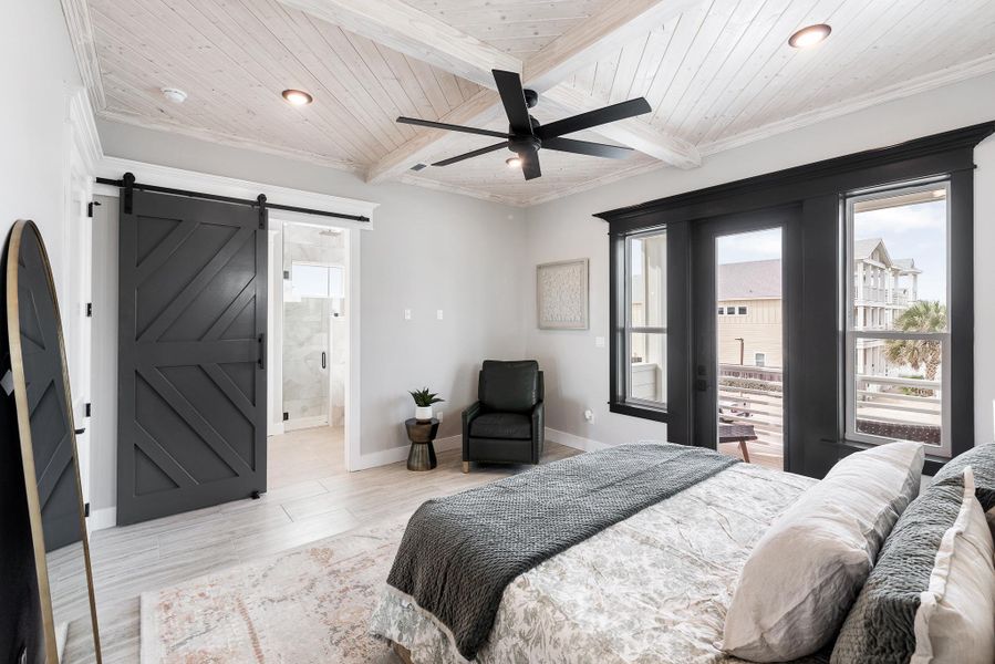 Bedroom featuring a barn door, light wood-style flooring, a wood ceiling with exposed beams, connected bathroom, and ornamental molding Bedroom featuring a barn door, light wood-style flooring, a wood ceiling with exposed beams, connected bathroom, and ornamental molding