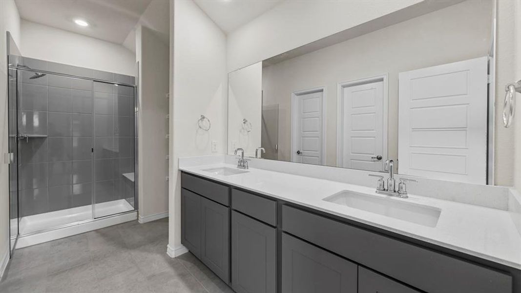 Bathroom featuring a dual vanity with undermount sinks, stone countertops, and gray cabinetry