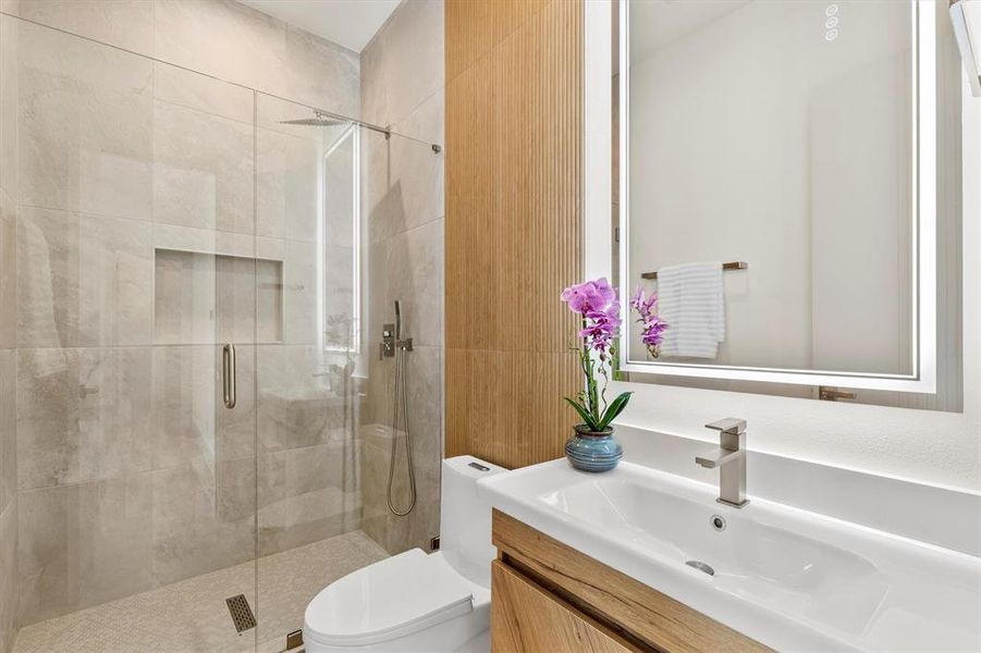 Bathroom with a shower with door, vanity, and toilet