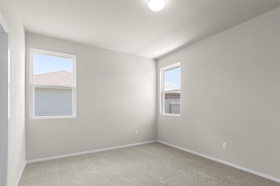 Empty room with light colored carpet and baseboards