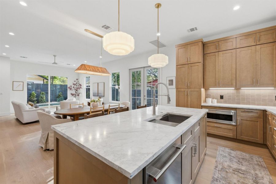 An open-concept living space integrates a well-appointed kitchen island, dining area, and living room, all illuminated by recessed lighting.