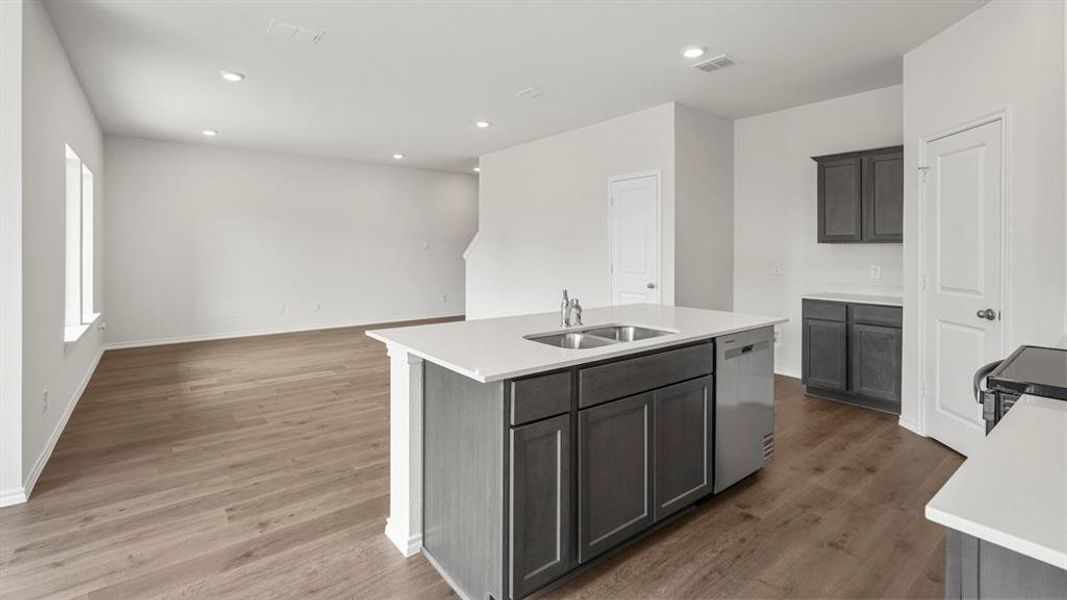 Open concept living area featuring light-toned flooring, white walls, recessed lighting, and windows providing natural light