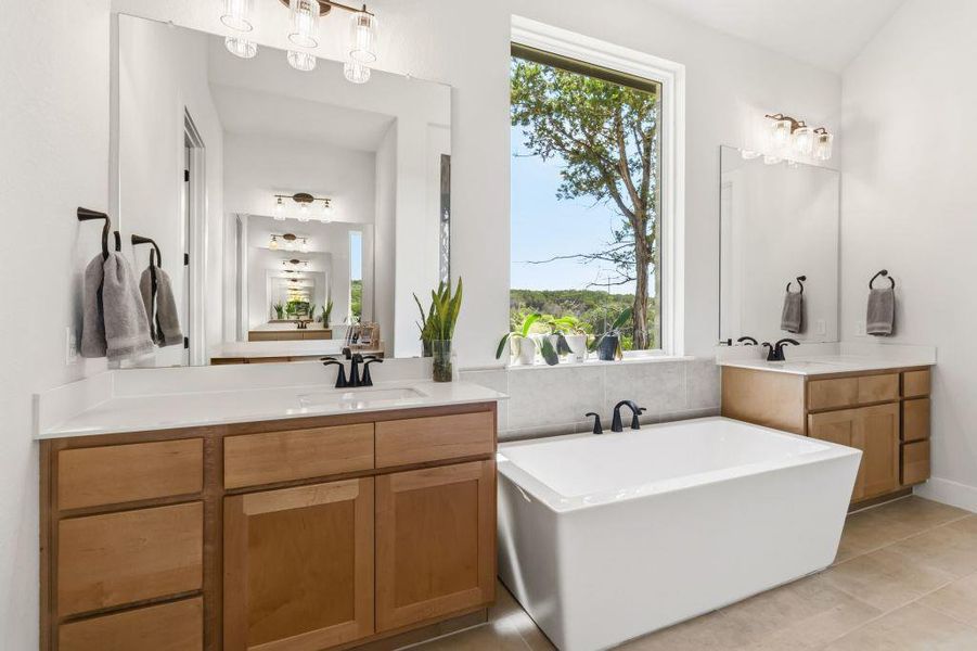 A tranquil primary bathroom featuring a freestanding tub and double vanity with serene outdoor views.