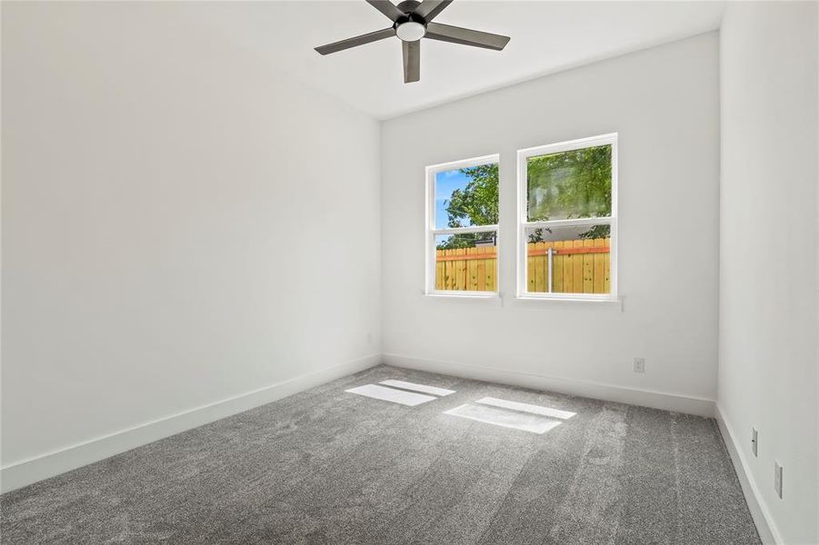 Carpeted spare room with baseboards and a ceiling fan