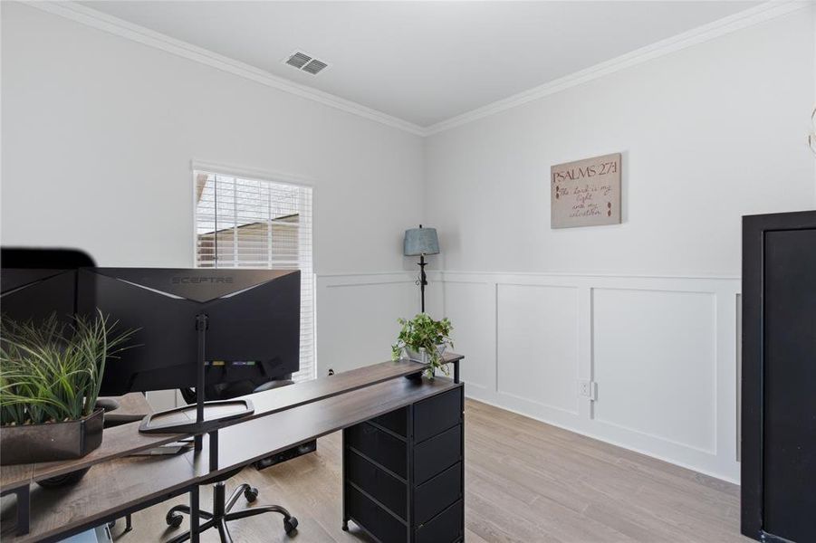 Room featuring light-toned wood-finish flooring, white walls, and wainscoting