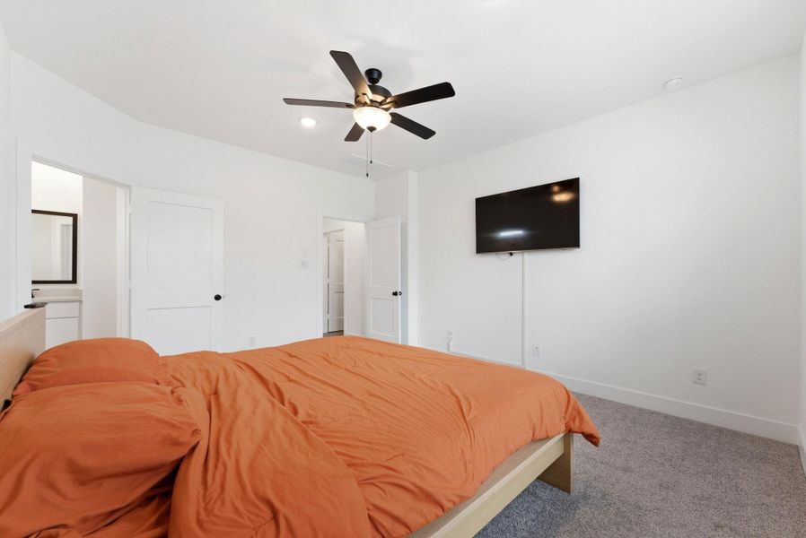 Relaxing owner’s suite featuring large windows, ceiling fan, and direct access to the ensuite bath.