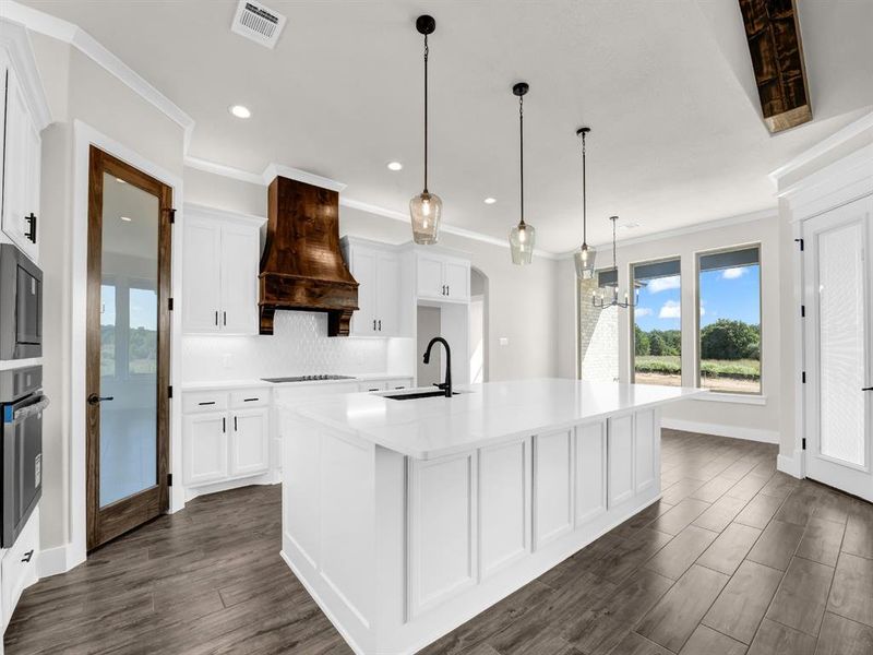Kitchen with white cabinetry, dark wood-style flooring, ornamental molding, decorative light fixtures, and backsplash