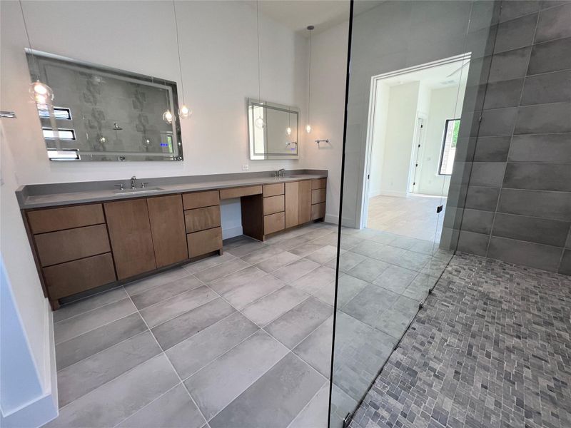 Bathroom with double vanity, light tile patterned floors, and a walk in shower