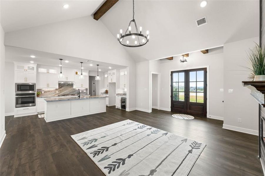 Unfurnished living room with recessed lighting, beam ceiling, high vaulted ceiling, dark wood-style floors, and french doors Unfurnished living room with recessed lighting, beam ceiling, high vaulted ceiling, dark wood-style floors, and french doors