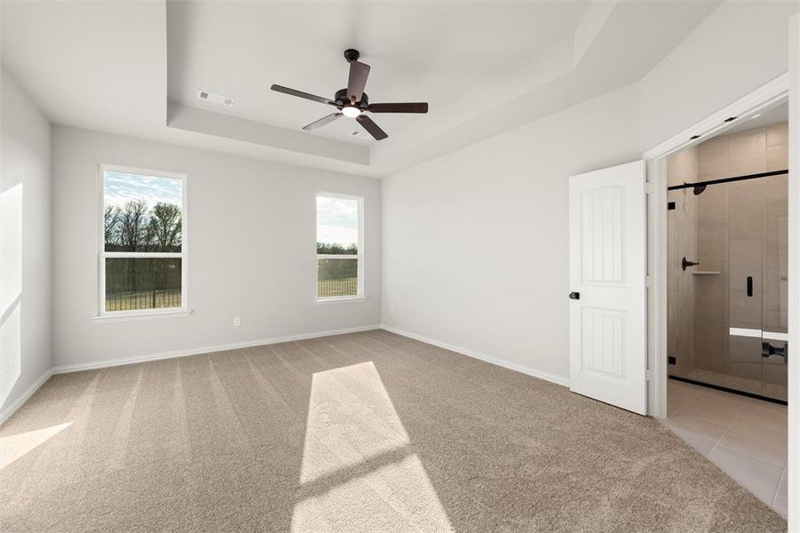 Unfurnished bedroom with a raised ceiling, light carpet, and ceiling fan Unfurnished bedroom with a raised ceiling, light carpet, and ceiling fan