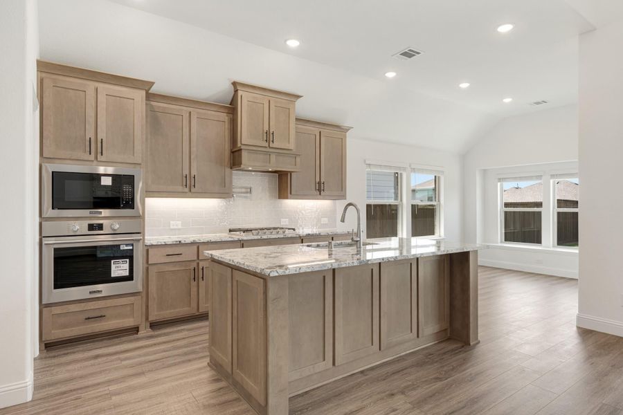 Kitchen with light wood cabinets, granite island, stainless steel appliances, and hardwood floors Kitchen with light wood cabinets, granite island, stainless steel appliances, and hardwood floors