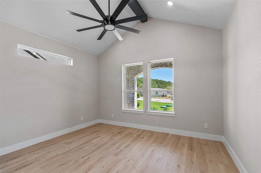 Empty room with ceiling fan, beamed ceiling, light hardwood / wood-style flooring, and high vaulted ceiling