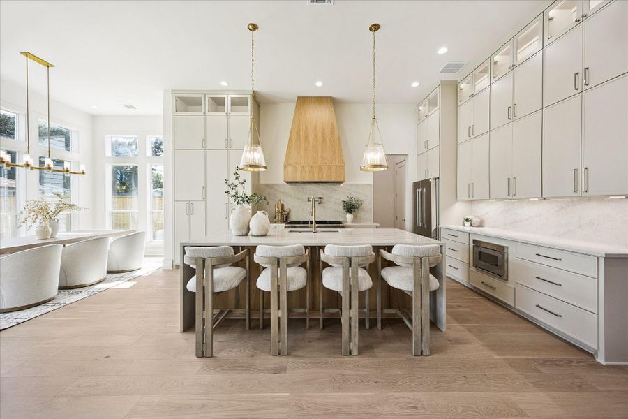 Clean lines meet custom craftsmanship in this bright, elegant kitchen, where floor to ceiling cabinetry, Taj Mahal quartzite counters and a seamless full slab backsplash create a beautifully tailored look. A statement white oak island, Visual Comfort lighting, solid brass details and a luxury Thermador appliance package add another layer of sophistication, with plenty of room to cook, serve and gather.