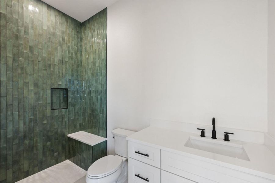 A chic primary bathroom showcases a walk-in shower with emerald-toned tile and a sleek vanity. A chic primary bathroom showcases a walk-in shower with emerald-toned tile and a sleek vanity.