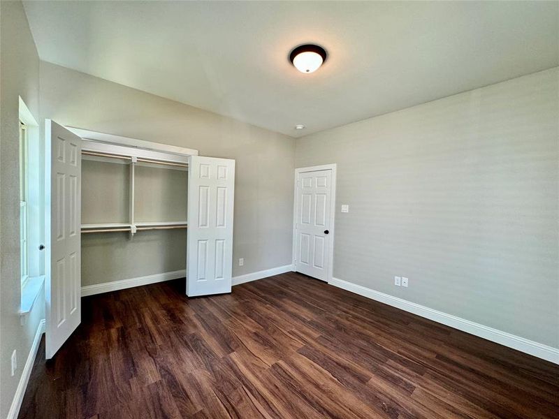 Unfurnished bedroom with dark hardwood / wood-style floors and a closet