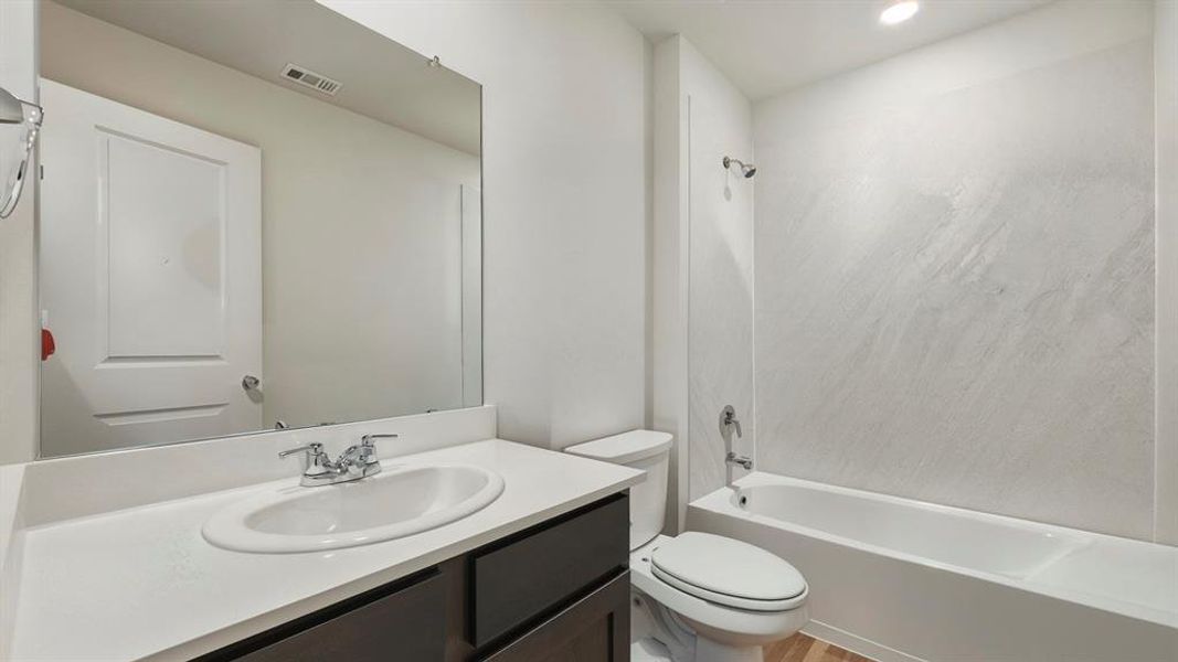 Full bathroom with vanity, bathing tub / shower combination, and light wood-style flooring