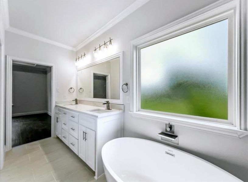 Full bathroom featuring double vanity, a freestanding tub, ornamental molding, and light tile patterned floors Full bathroom featuring double vanity, a freestanding tub, ornamental molding, and light tile patterned floors