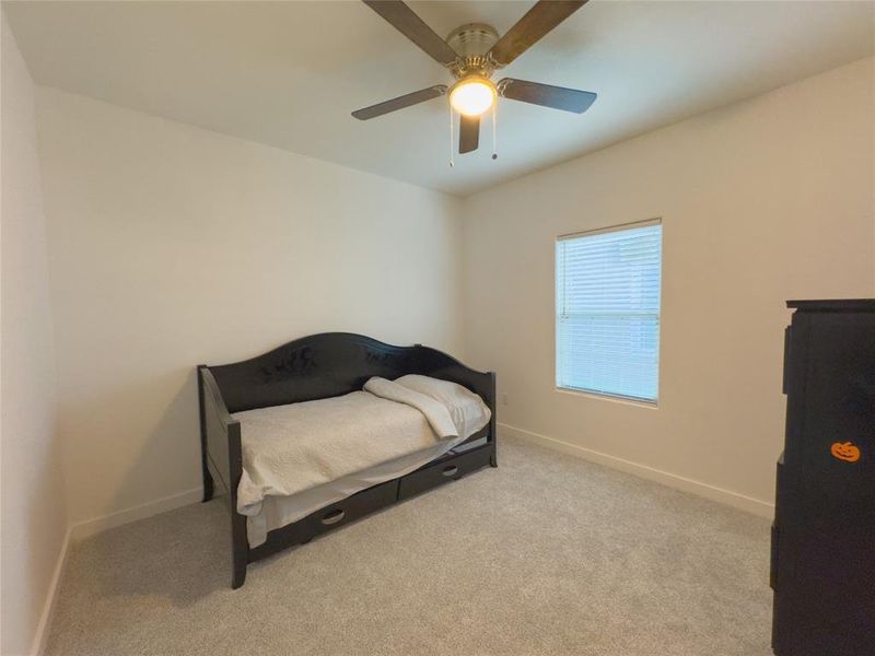 Carpeted bedroom featuring ceiling fan, and window covering