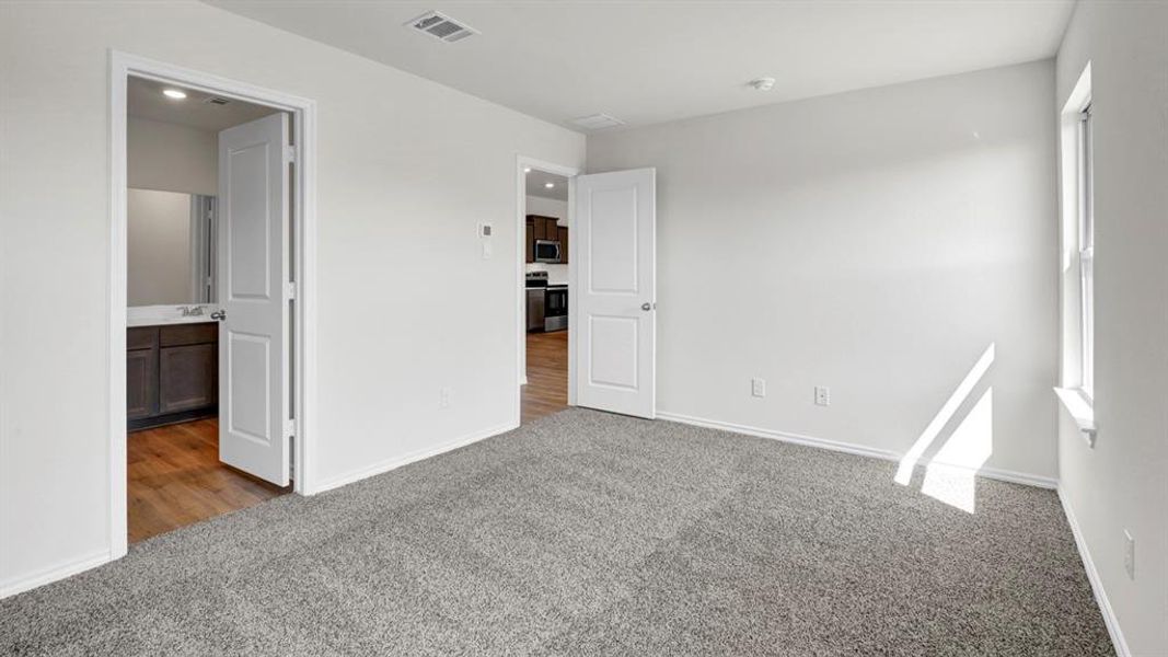 Unfurnished bedroom featuring light carpet and connected bathroom