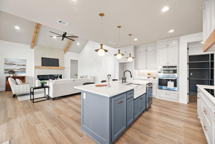 Kitchen with white cabinets, a ceiling fan, hanging light fixtures, light stone countertops, and a fireplace Kitchen with white cabinets, a ceiling fan, hanging light fixtures, light stone countertops, and a fireplace