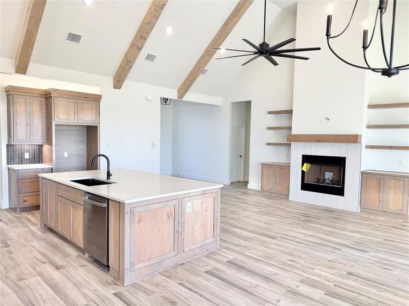 Kitchen with visible vents, dishwasher, open floor plan, a fireplace, and a sink