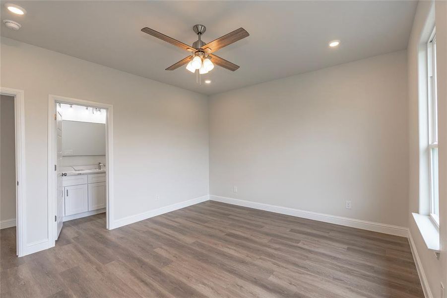 Unfurnished bedroom with wood-type flooring, connected bathroom, and ceiling fan