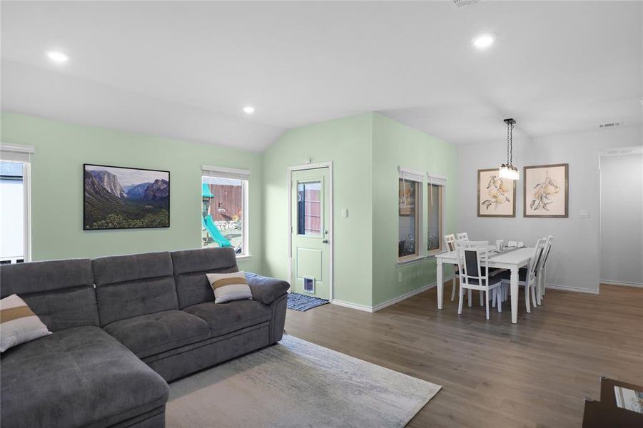 Living room with recessed lighting, dark wood-style flooring, and vaulted ceiling