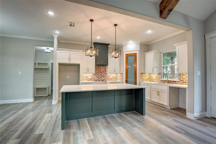 Kitchen with white cabinetry, a center island, and light wood-type flooring