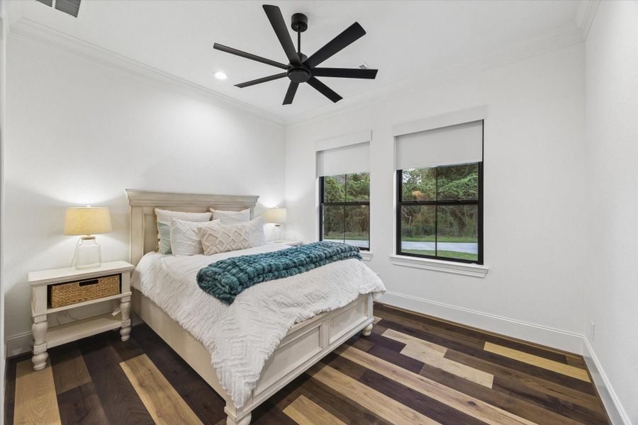This beautifully appointed secondary suite located on the first floor offers a serene retreat where comfort meets refined design. Oversized windows welcome natural light, while custom built-ins and thoughtfully selected finishes create an inviting atmosphere for family or guests.